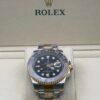 Rolex — esfera negra con doble huso horario, bisel gris y dorado y brazalete bicolor
