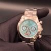 Rolex — cronógrafo con esfera turquesa y detalles rojos, caja y brazalete oro rosa