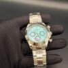 Rolex — cronógrafo con esfera turquesa y detalles rojos, brazalete de acero