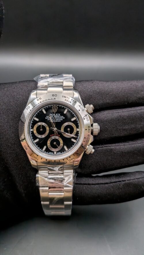 Rolex — cronógrafo con esfera negra y aros dorados, bisel de acero y brazalete de acero