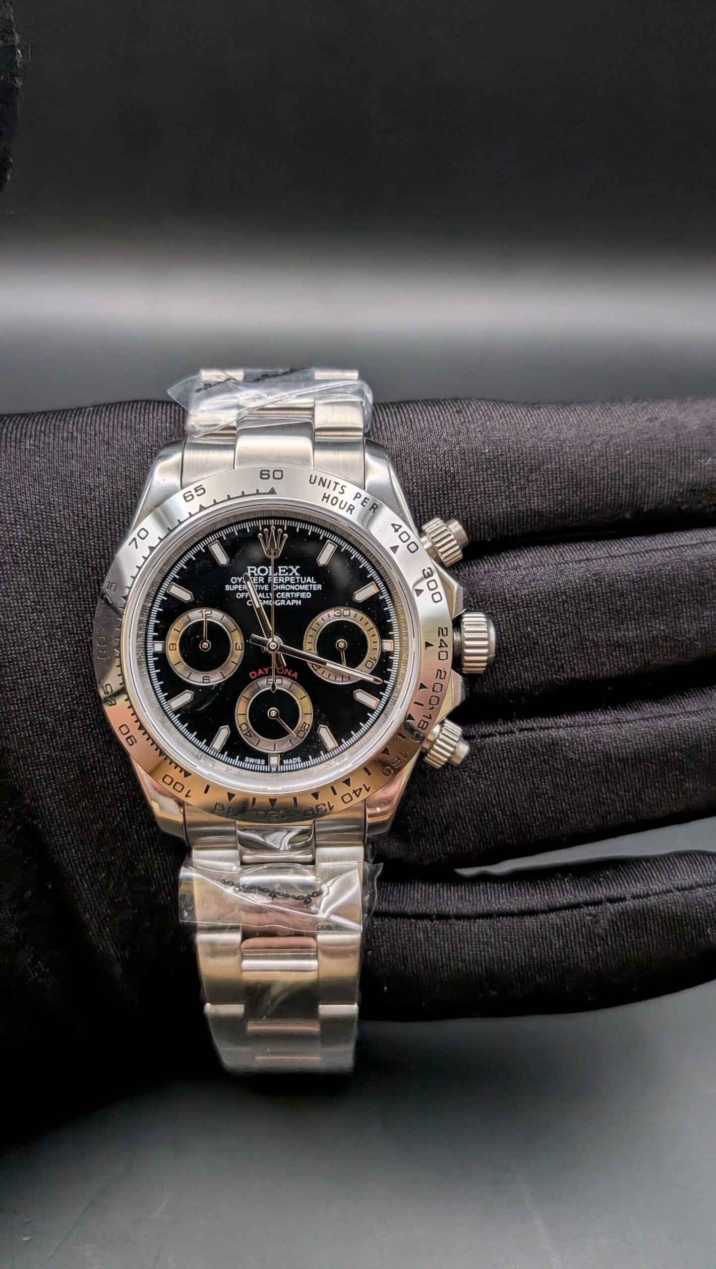 Rolex — cronógrafo con esfera negra y aros dorados, bisel de acero y brazalete de acero