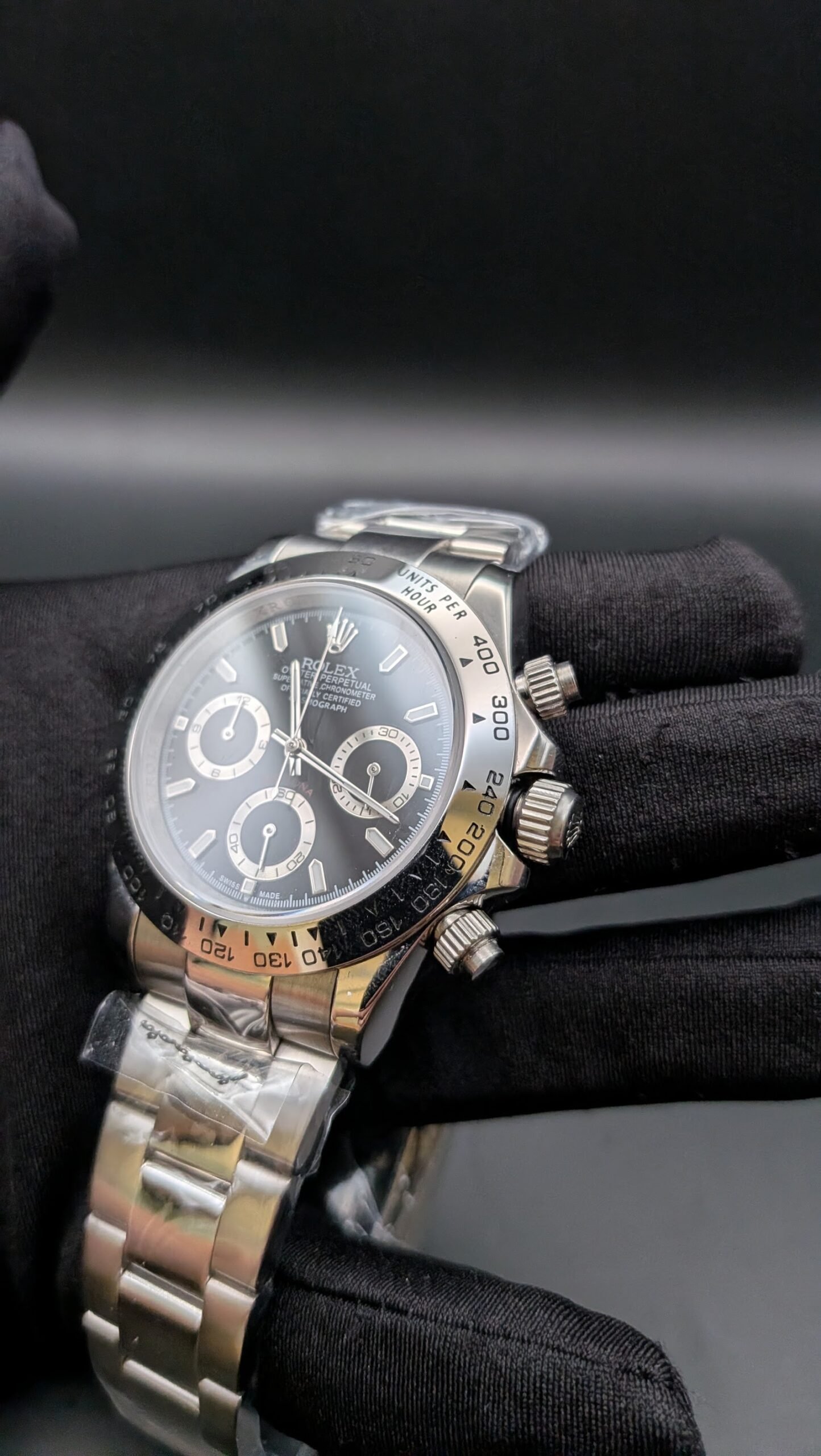 Rolex — cronógrafo con esfera negra y aros dorados, bisel de acero y brazalete de acero
