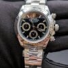 Rolex — cronógrafo con esfera negra y aros dorados, bisel de acero y brazalete de acero