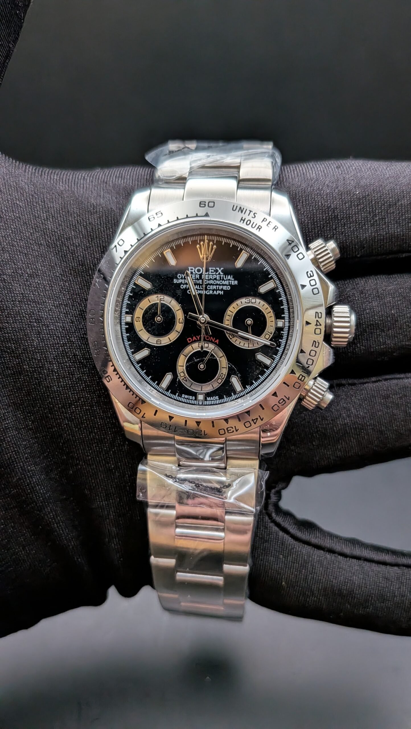 Rolex — cronógrafo con esfera negra y aros dorados, bisel de acero y brazalete de acero
