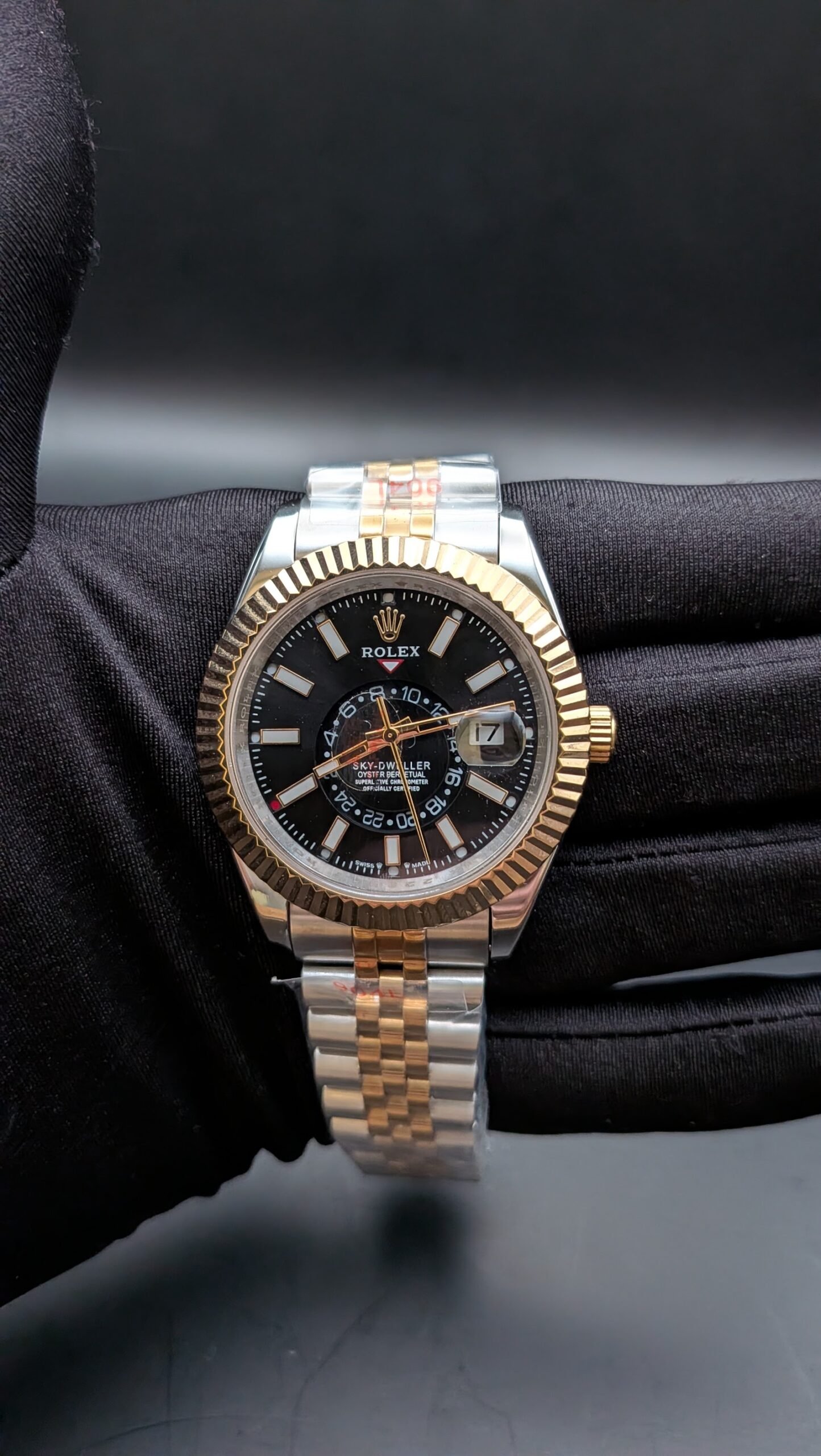 Rolex — esfera negra con calendario anual, bisel dorado estriado y brazalete jubilee bicolor