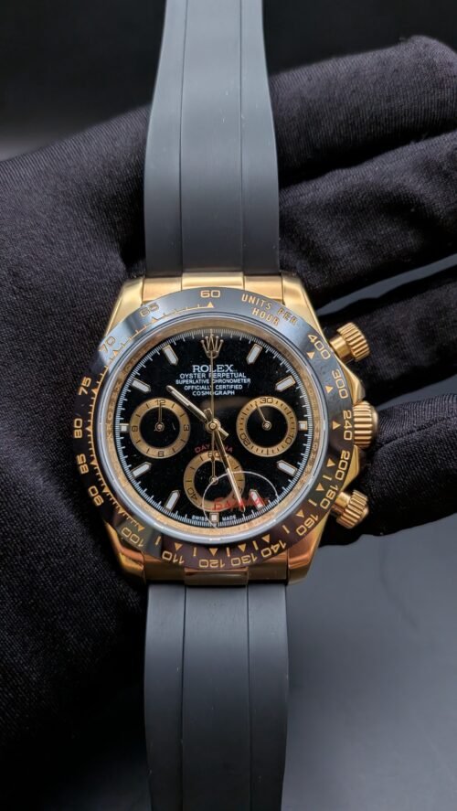 Rolex — cronógrafo con esfera negra, caja dorada y correa de caucho gris