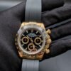 Rolex — cronógrafo con esfera negra, caja dorada y correa de caucho gris