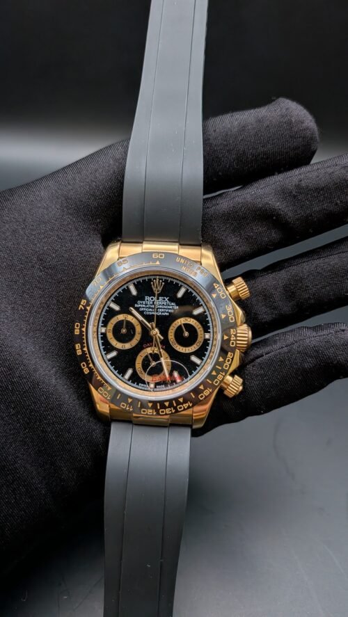 Rolex — cronógrafo con esfera negra, caja dorada y correa de caucho gris