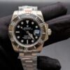 Rolex — esfera negra, bisel negro y brazalete de acero en mano