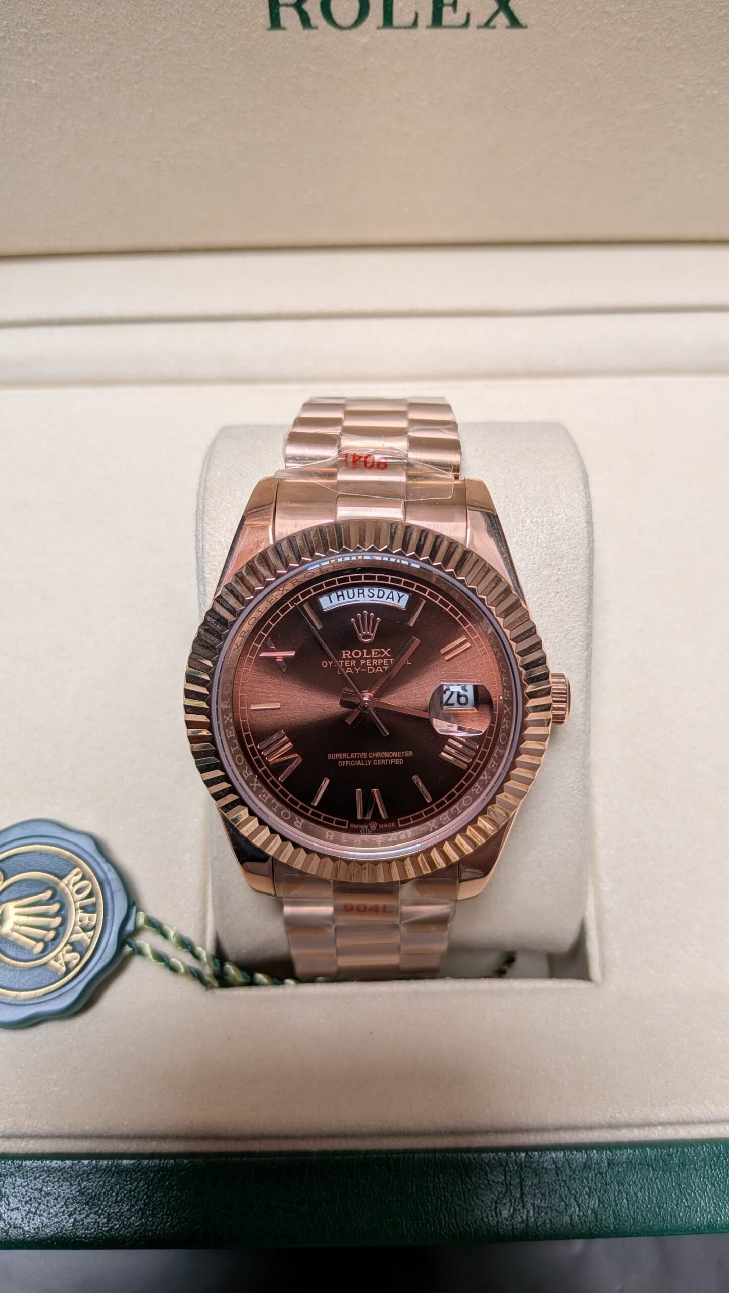 Rolex — esfera chocolate con día y fecha, bisel estriado y brazalete oro rosa