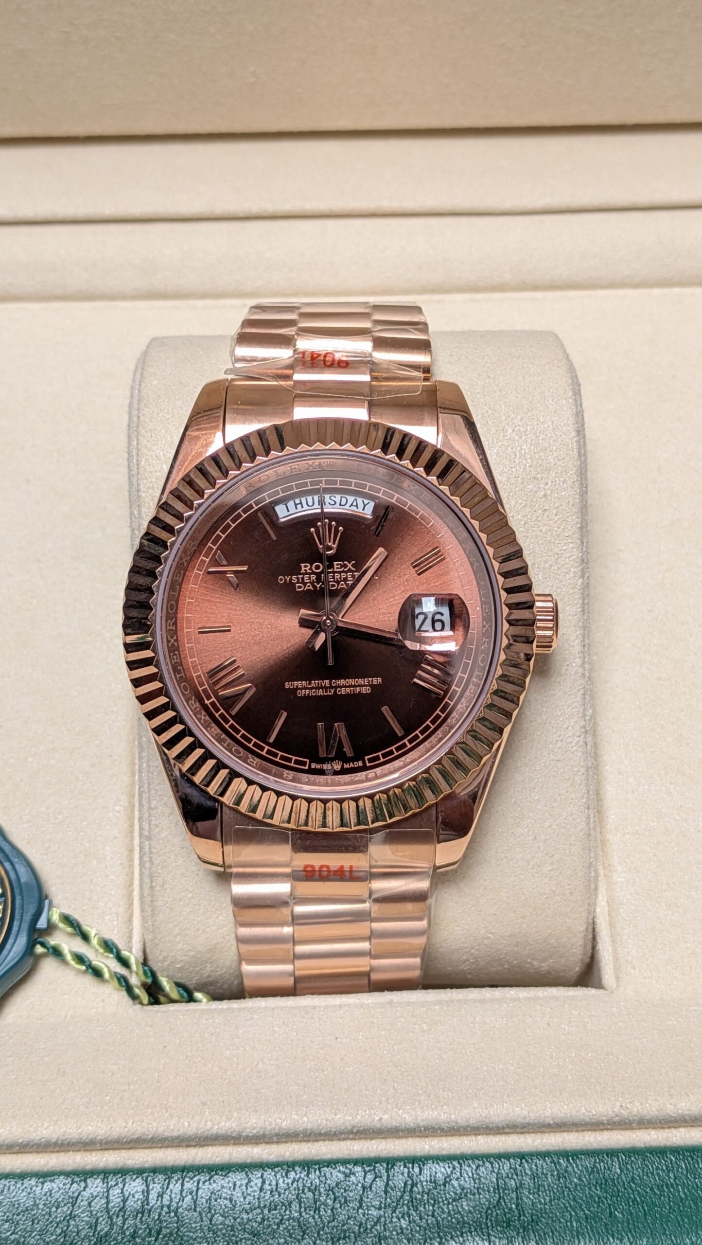 Rolex — esfera chocolate con día y fecha, bisel estriado y brazalete oro rosa
