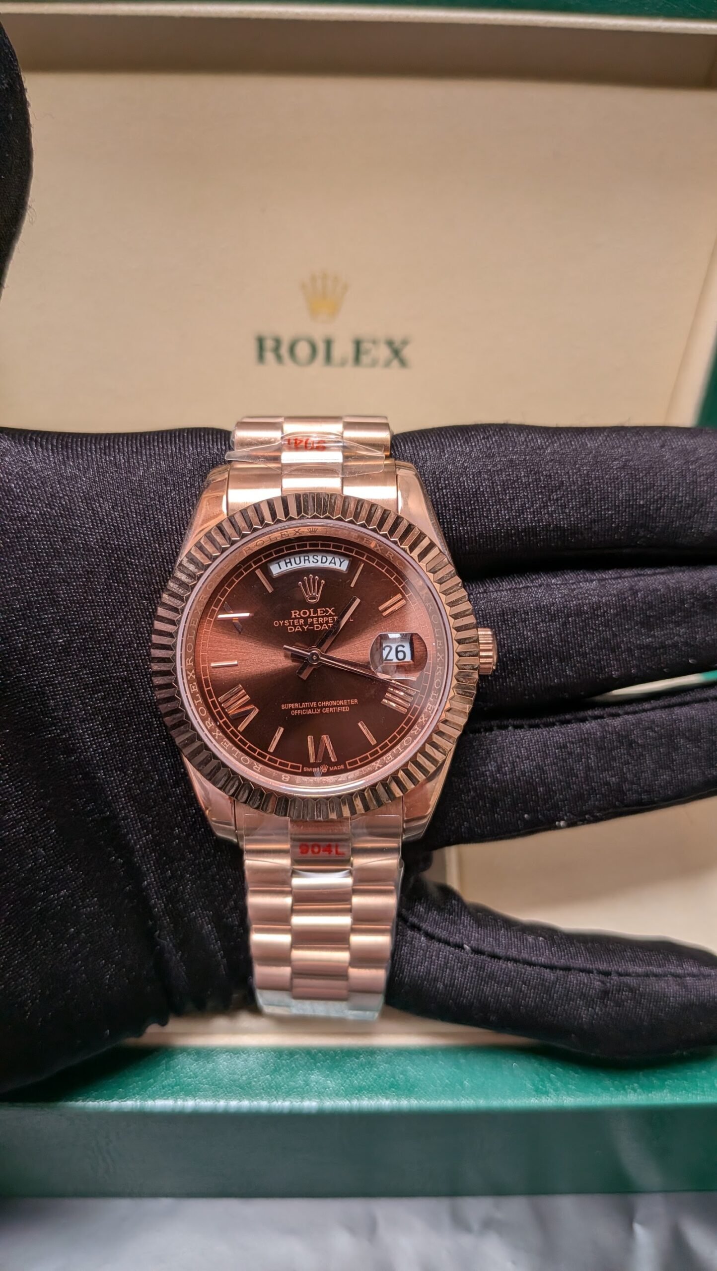 Rolex — esfera chocolate con día y fecha, bisel estriado y brazalete oro rosa