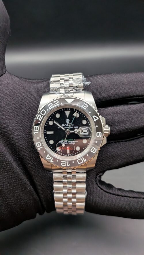 Rolex — esfera negra con doble huso horario, bisel gris y negro y brazalete de acero