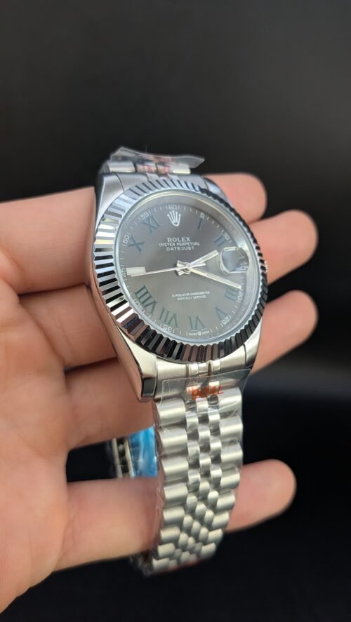 Rolex — esfera gris con números romanos verdes, bisel estriado y brazalete jubilee de acero