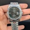 Rolex — esfera gris con números romanos verdes, bisel estriado y brazalete jubilee de acero