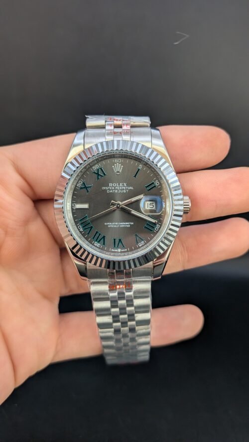 Rolex — esfera gris con números romanos verdes, bisel estriado y brazalete jubilee de acero