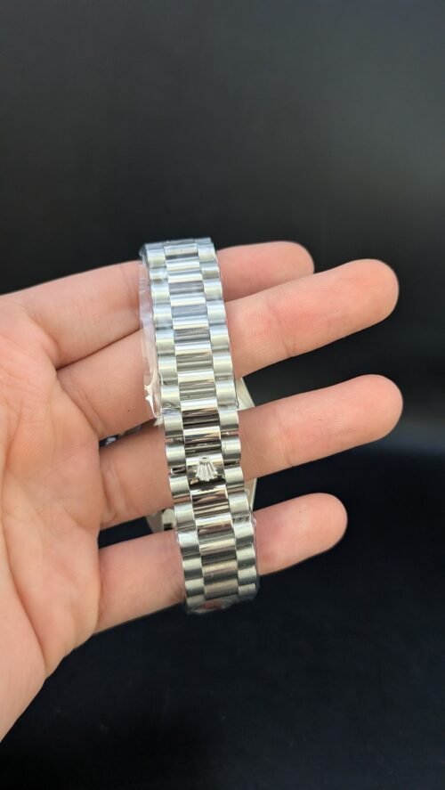 Rolex — esfera plateada con día y fecha, bisel estriado y brazalete de acero