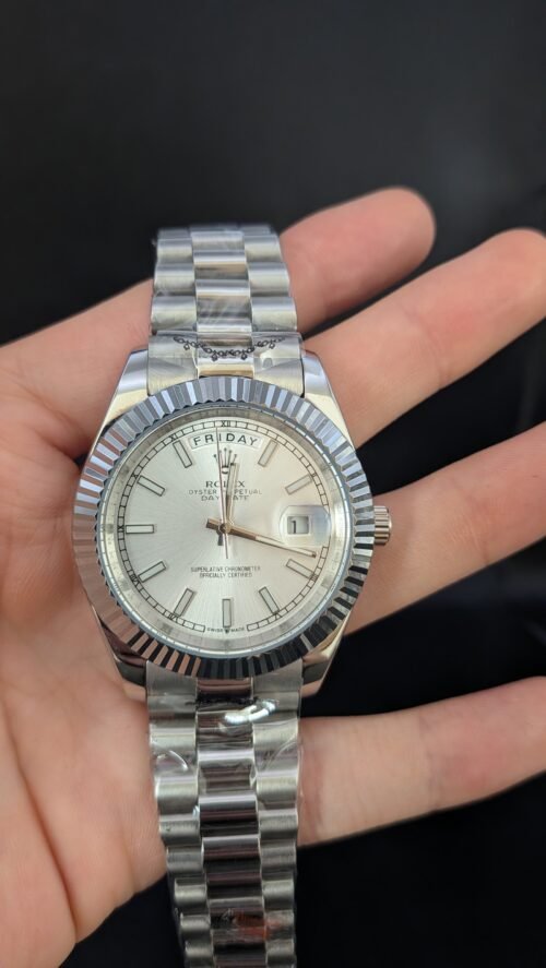 Rolex — esfera plateada con día y fecha, bisel estriado y brazalete de acero