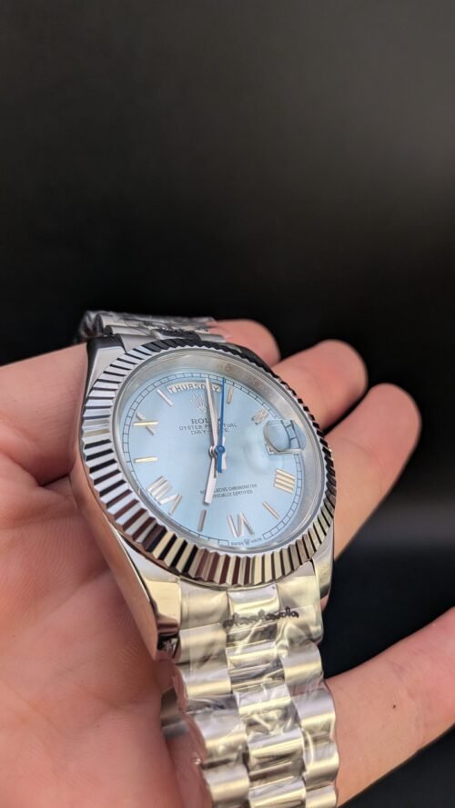Rolex — esfera azul hielo con números romanos, día y fecha, bisel estriado y brazalete de acero