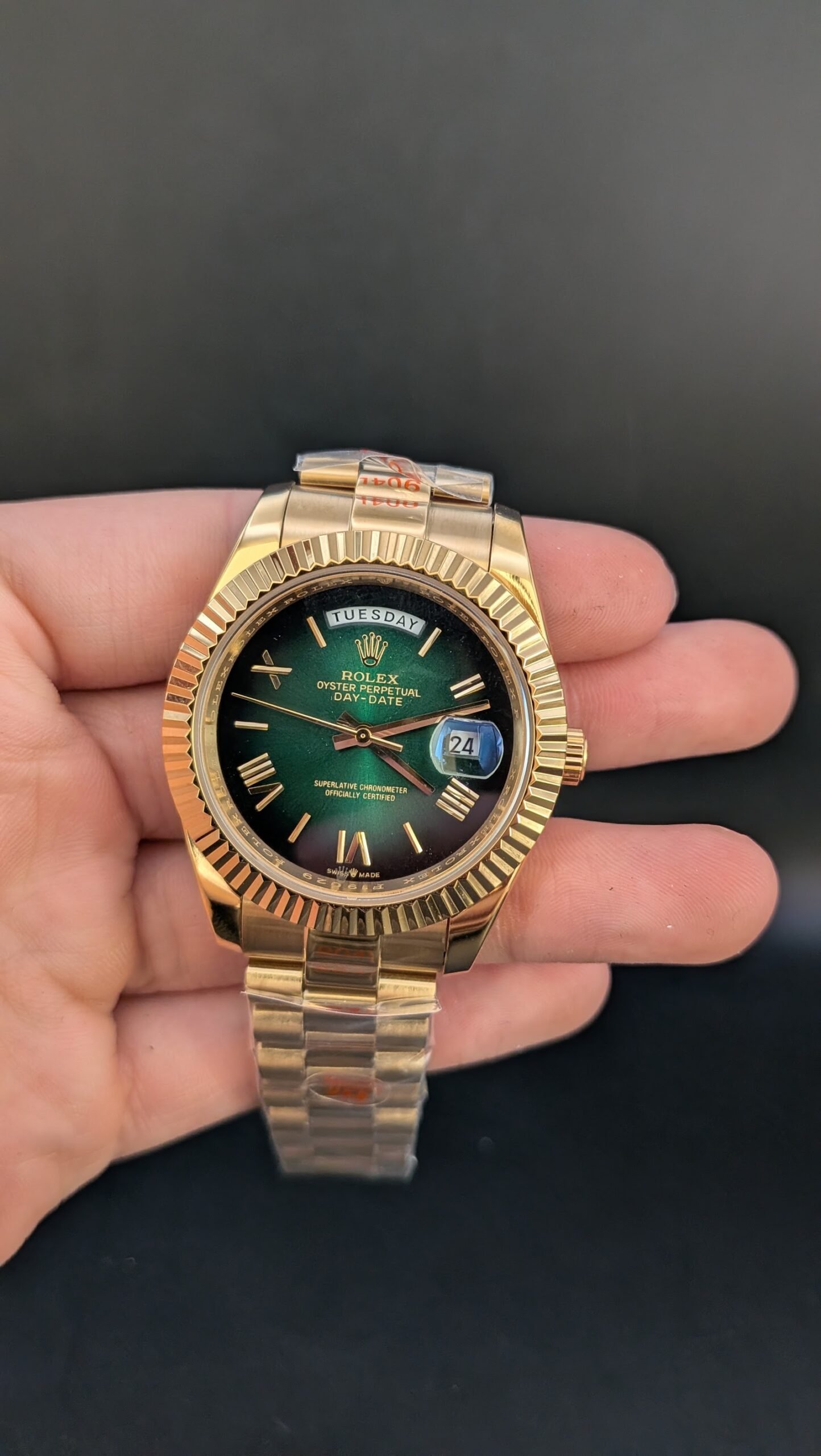 Rolex — esfera verde degradada con números romanos, día y fecha, caja y brazalete dorados
