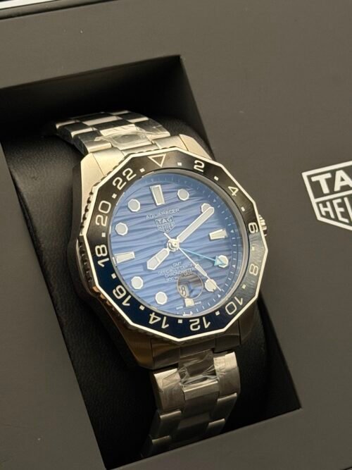 TAG Heuer — esfera azul ondulada con doble huso horario, bisel azul y brazalete de acero