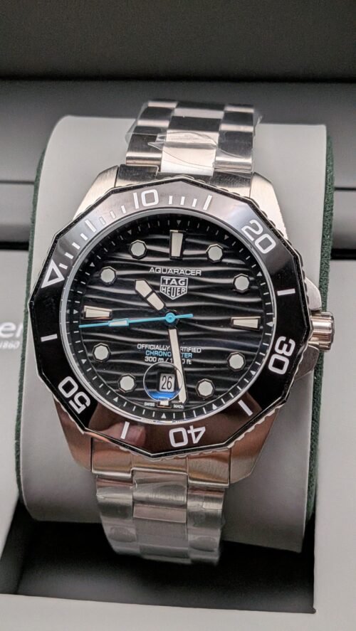 TAG Heuer — esfera negra ondulada con detalle celeste, bisel negro y brazalete de acero