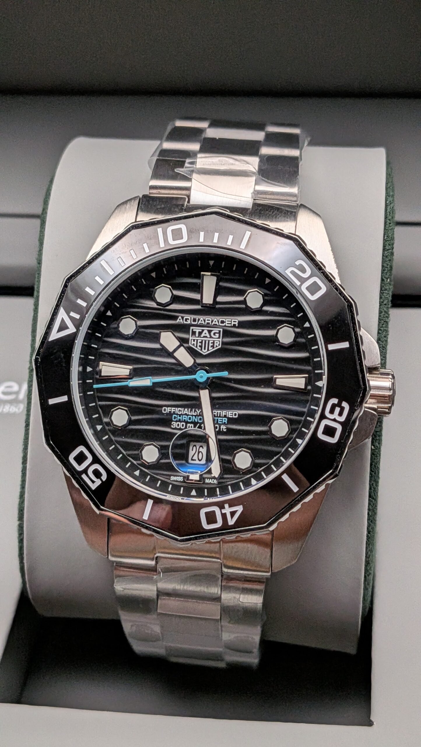TAG Heuer — esfera negra ondulada con detalle celeste, bisel negro y brazalete de acero