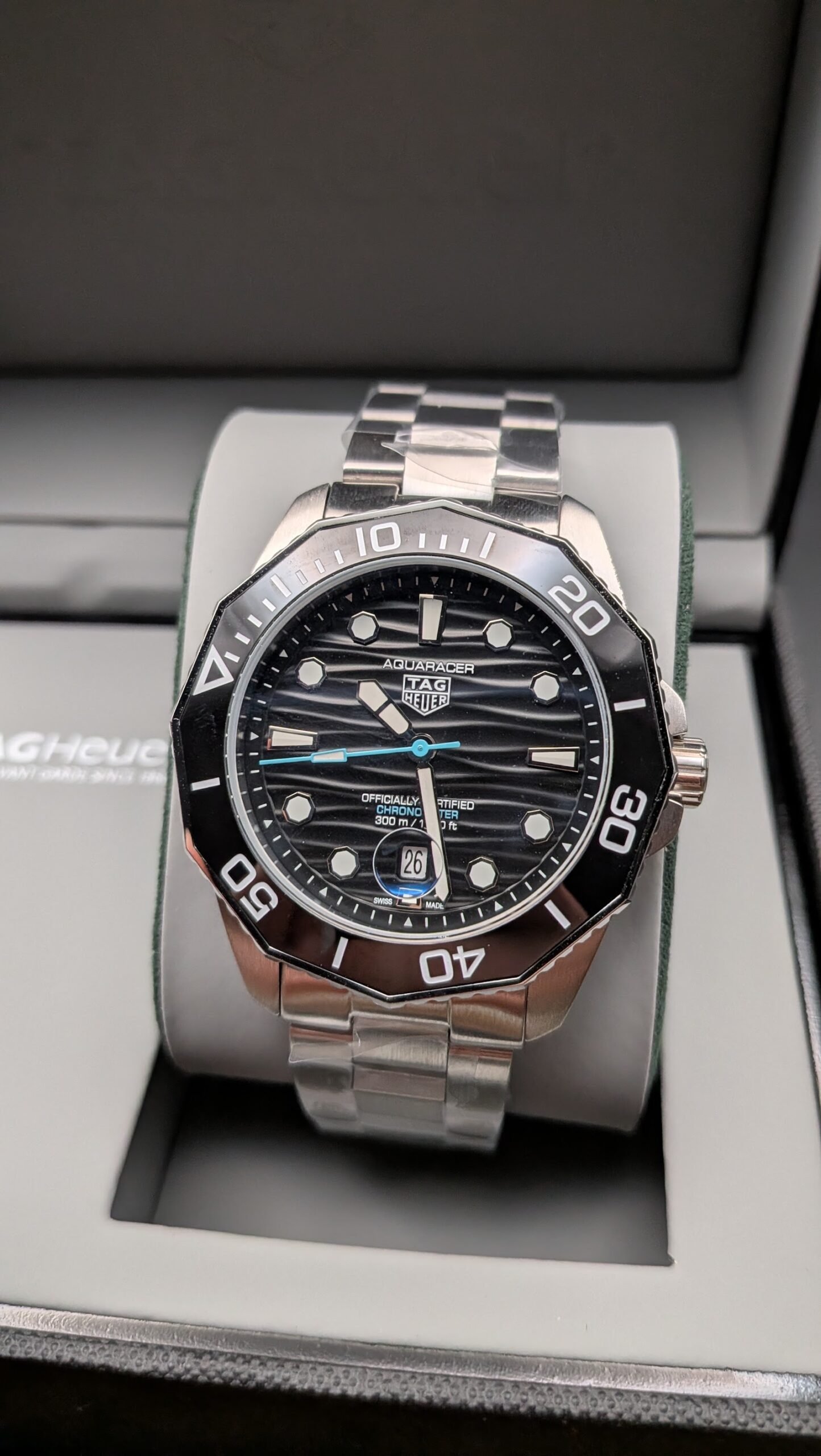 TAG Heuer — esfera negra ondulada con detalle celeste, bisel negro y brazalete de acero