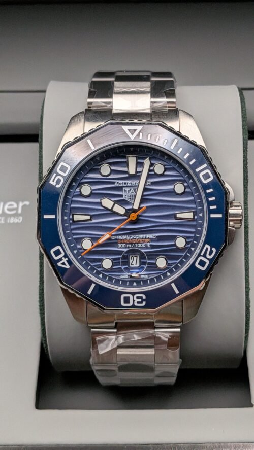 TAG Heuer — esfera azul ondulada con detalle naranja, bisel azul y brazalete de acero