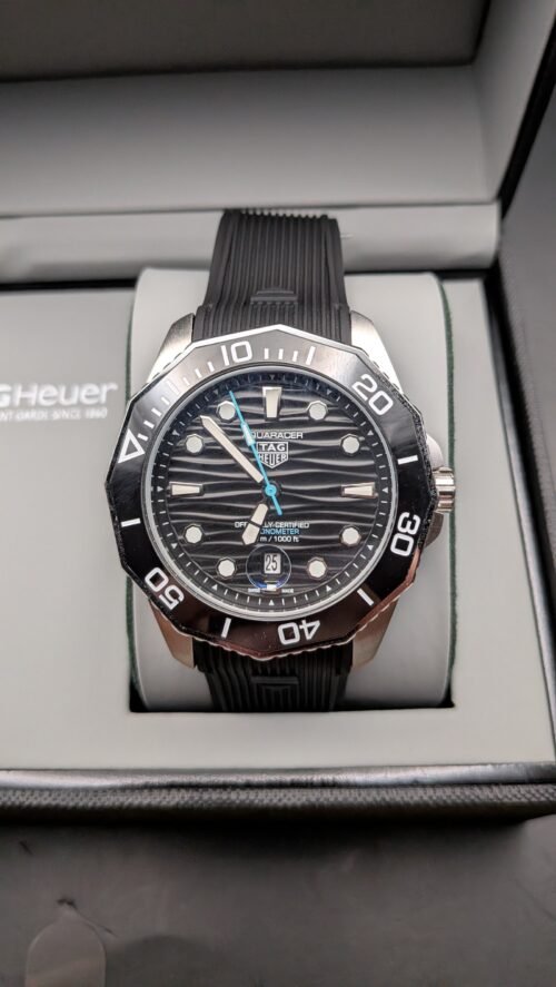 TAG Heuer — esfera negra ondulada con detalle celeste, bisel negro y correa de caucho negra