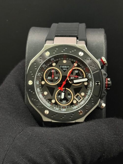 Tissot — cronógrafo con esfera negra y detalles rojos, caja negra y correa de caucho negra