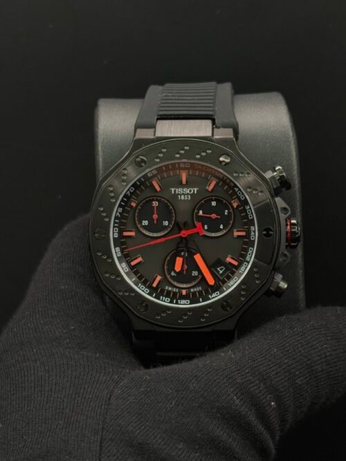 Tissot — cronógrafo con esfera negra y detalles naranjas, caja negra y correa de caucho negra