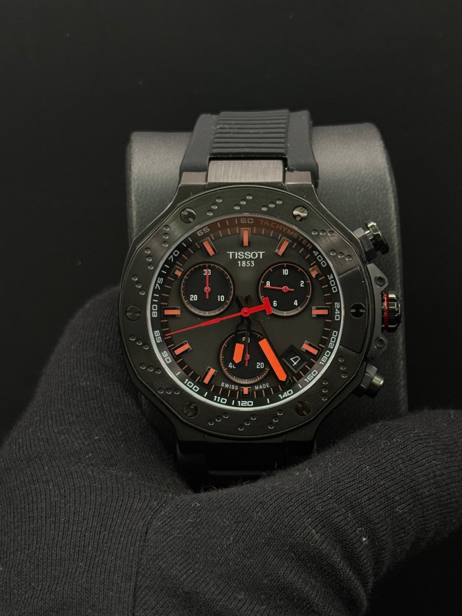 Tissot — cronógrafo con esfera negra y detalles naranjas, caja negra y correa de caucho negra
