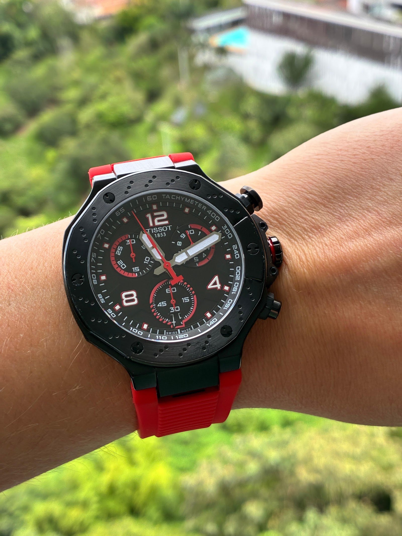 Tissot — cronógrafo con esfera negra y detalles rojos, caja negra y correa de caucho roja