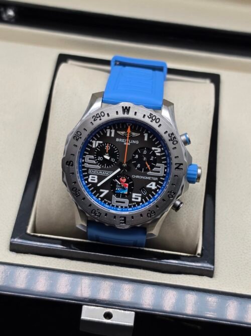 Breitling — cronógrafo con esfera negra, detalles azules, caja de acero y correa azul celeste