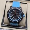 Breitling — cronógrafo negro con detalles celestes y correa celeste