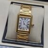 Cartier — caja rectangular dorada, esfera blanca con números romanos y brazalete dorado