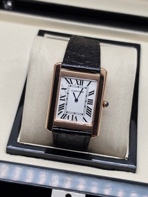 Cartier — caja rectangular oro rosa, esfera blanca con números romanos y correa de cuero negra