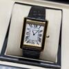 Cartier — caja rectangular dorada, esfera blanca con números romanos y correa negra texturizada