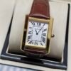 Cartier — caja rectangular dorada, esfera blanca con números romanos y correa de cuero vinotinto
