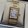 Cartier — caja rectangular dorada, esfera blanca con números romanos y brazalete dorado