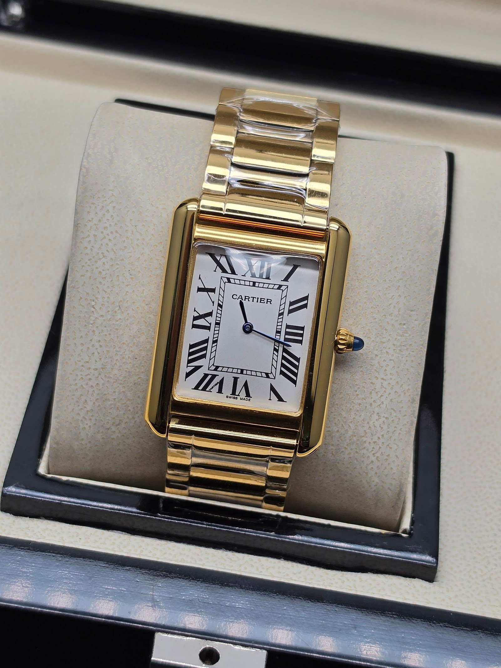 Cartier — caja rectangular dorada, esfera blanca con números romanos y brazalete dorado