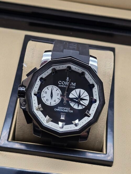 Corum — cronógrafo con esfera negra, subesferas blancas y correa de caucho negra