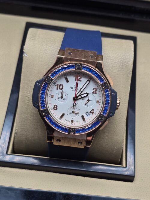 Hublot — cronógrafo con esfera blanca, bisel con piedras azules y caja oro rosa, correa azul