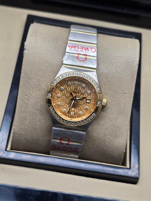Omega — esfera dorada texturizada con brillantes y brazalete bicolor