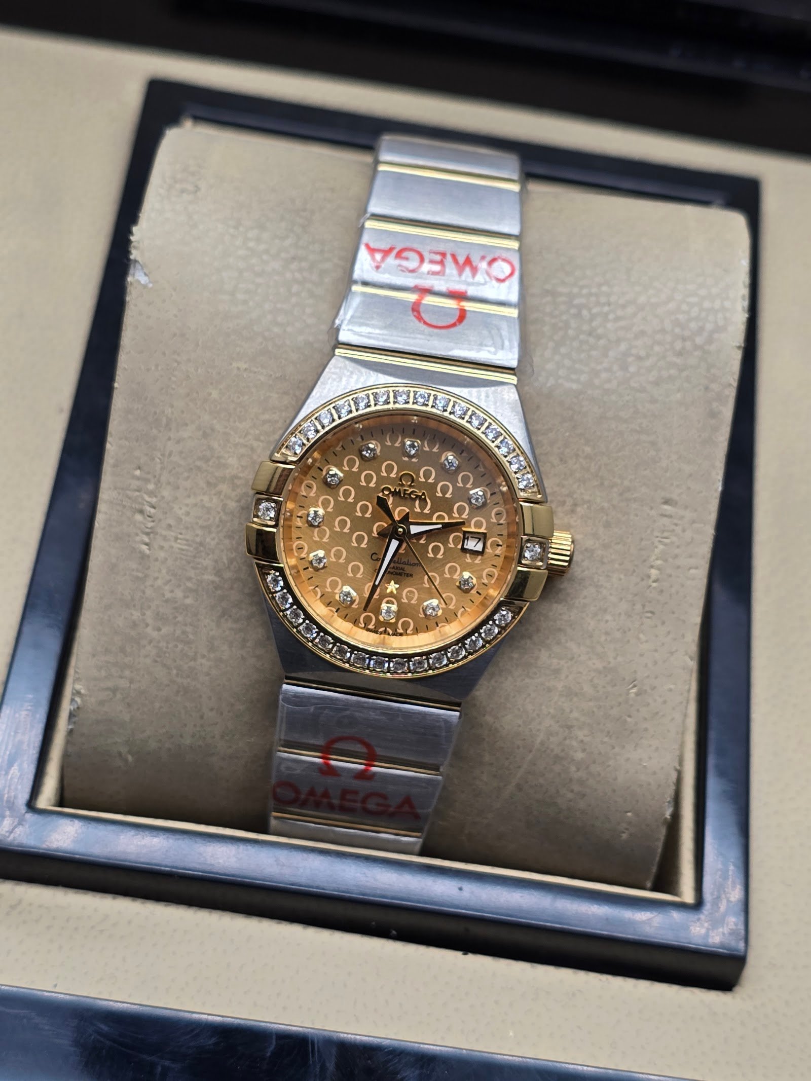 Omega — esfera dorada texturizada con brillantes y brazalete bicolor