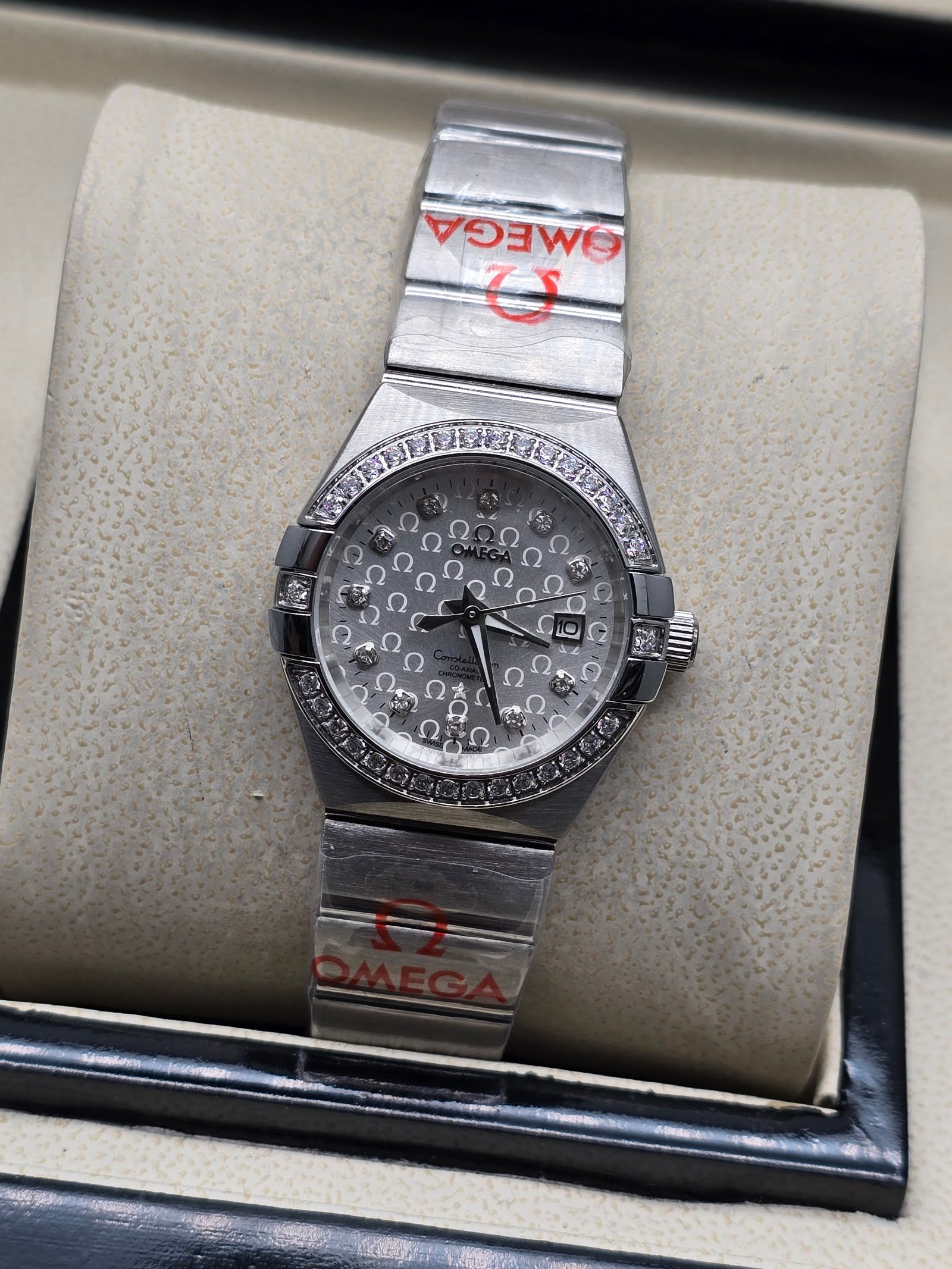 Omega — esfera plateada texturizada con brillantes y brazalete de acero