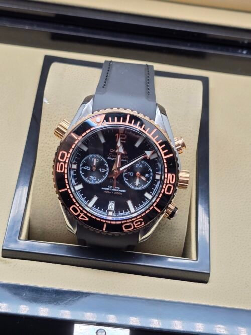 Omega — cronógrafo con esfera negra, bisel oro rosa y correa de caucho gris