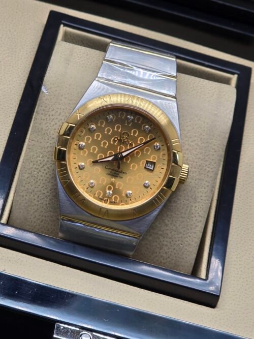 Omega — esfera dorada texturizada, bisel dorado y brazalete bicolor