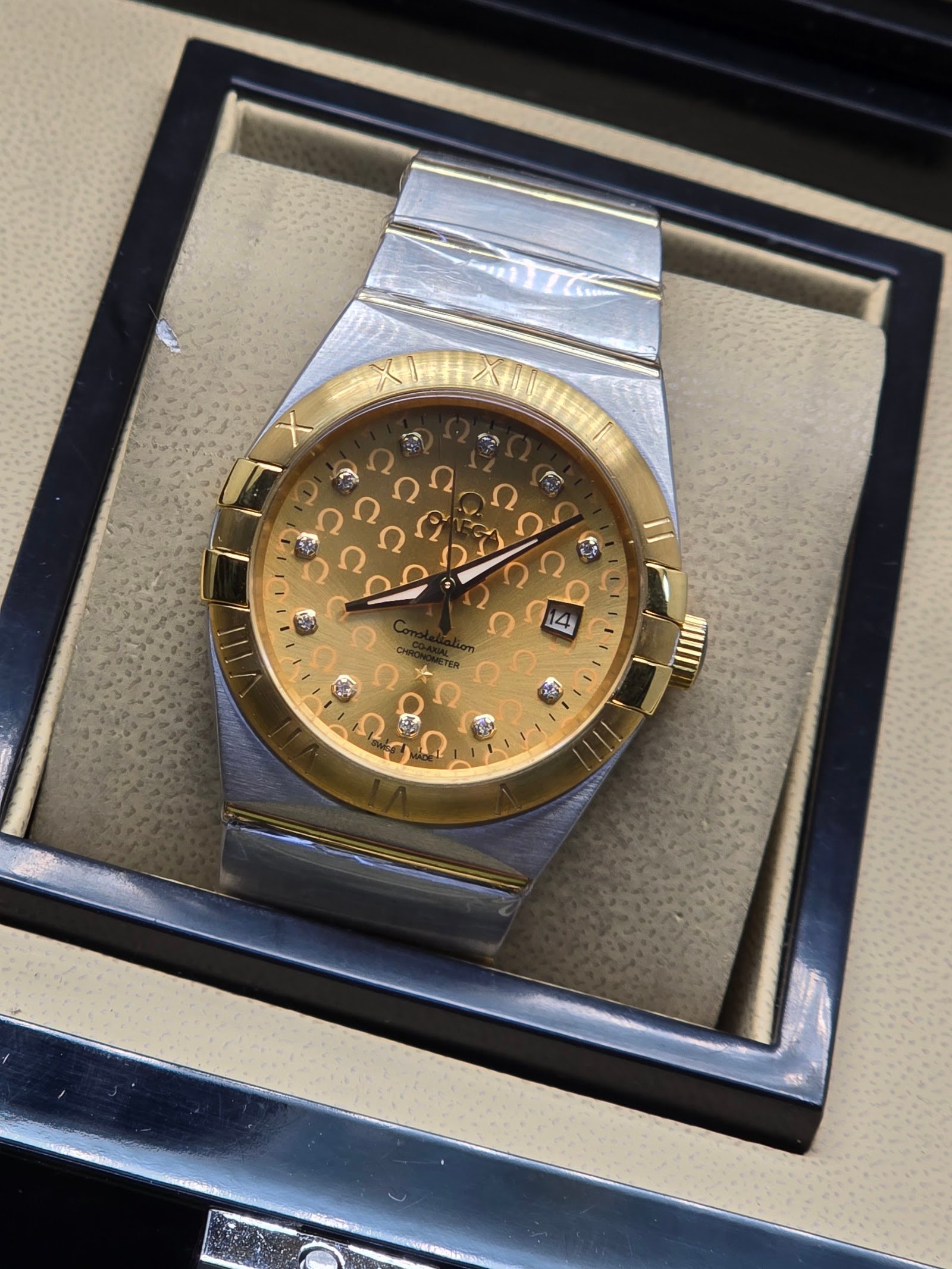 Omega — esfera dorada texturizada, bisel dorado y brazalete bicolor